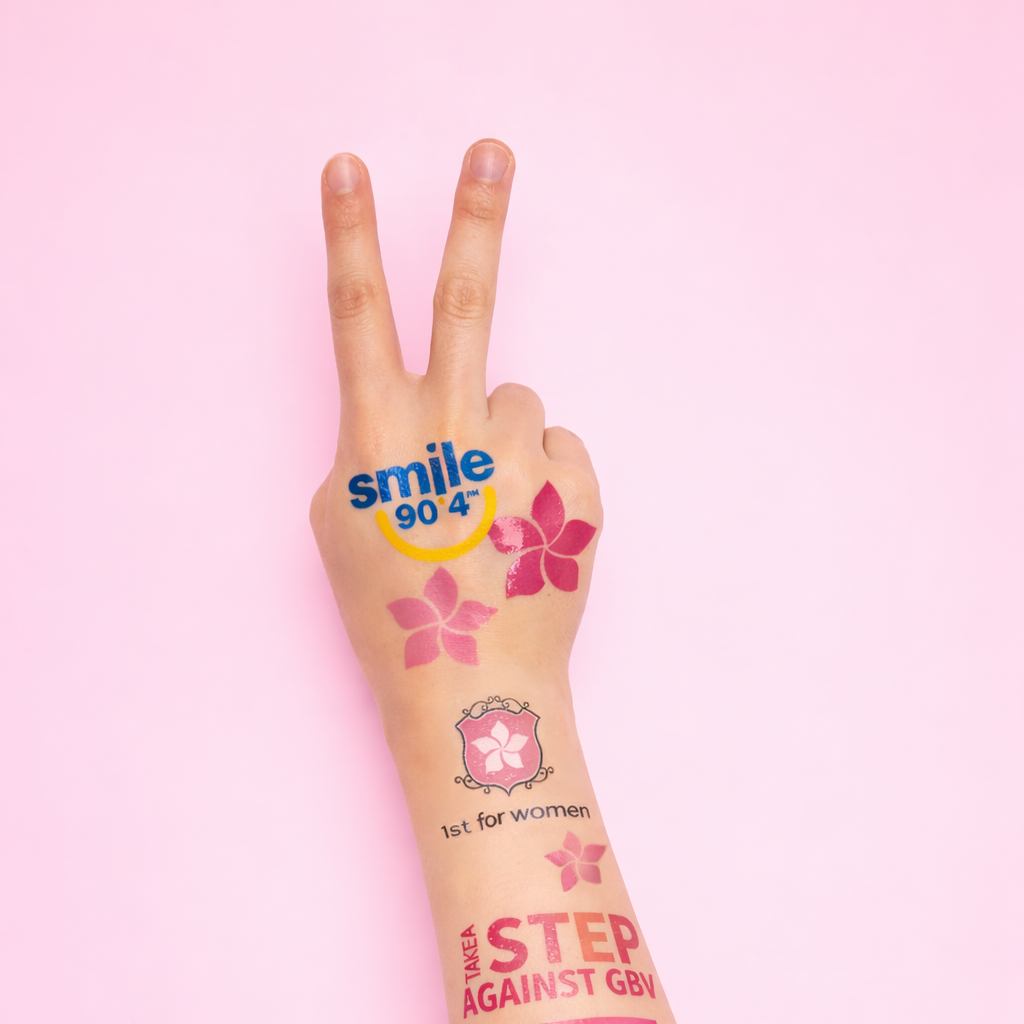 Hand making a peace sign with visible tattoos on a pink background